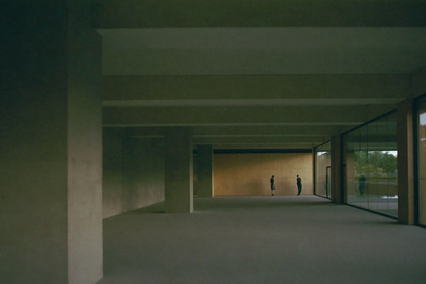 Two people in a large, empty concrete hall